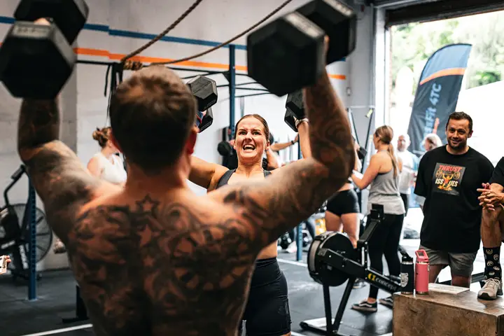 Woman with a barbell on her back, chalk dust around her