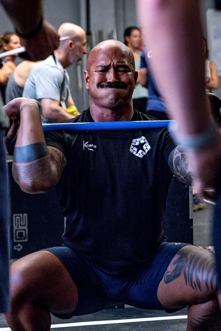Two athletes side by side with barbells